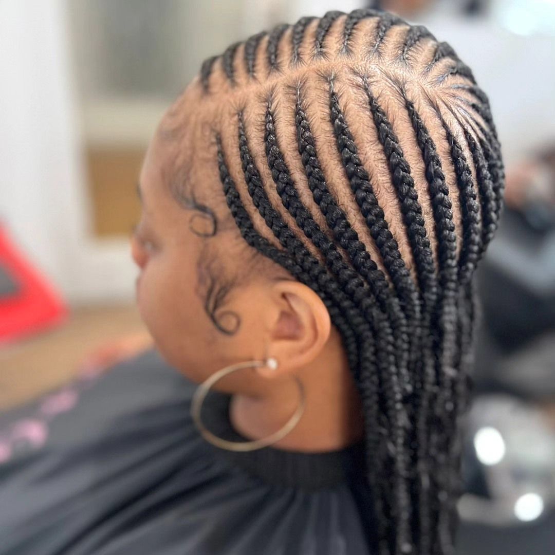 Person with cornrow braids and hoop earrings. Braids begin at the scalp.