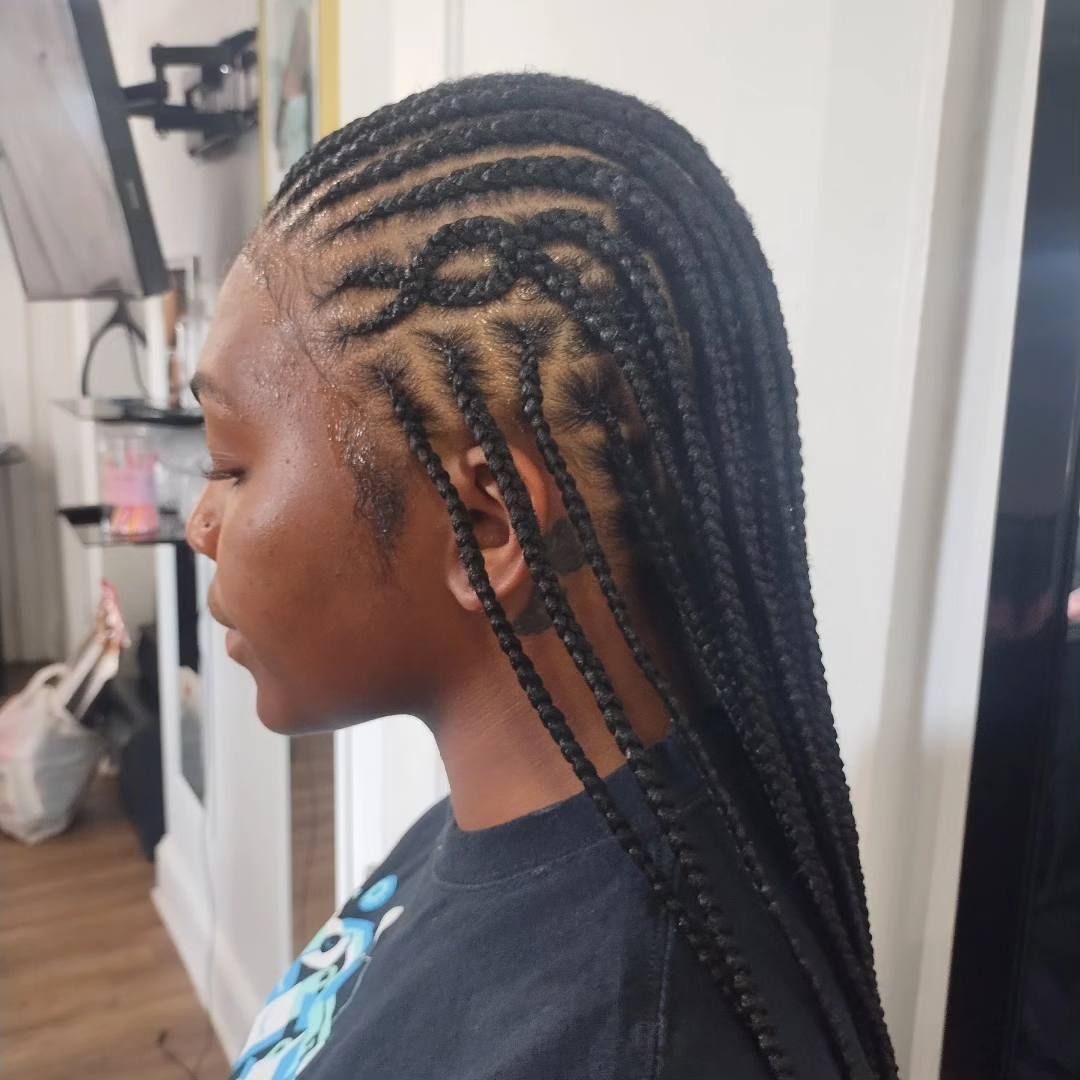 Woman with black braided hairstyle. Braids create a design on the side of the head. Indoors.