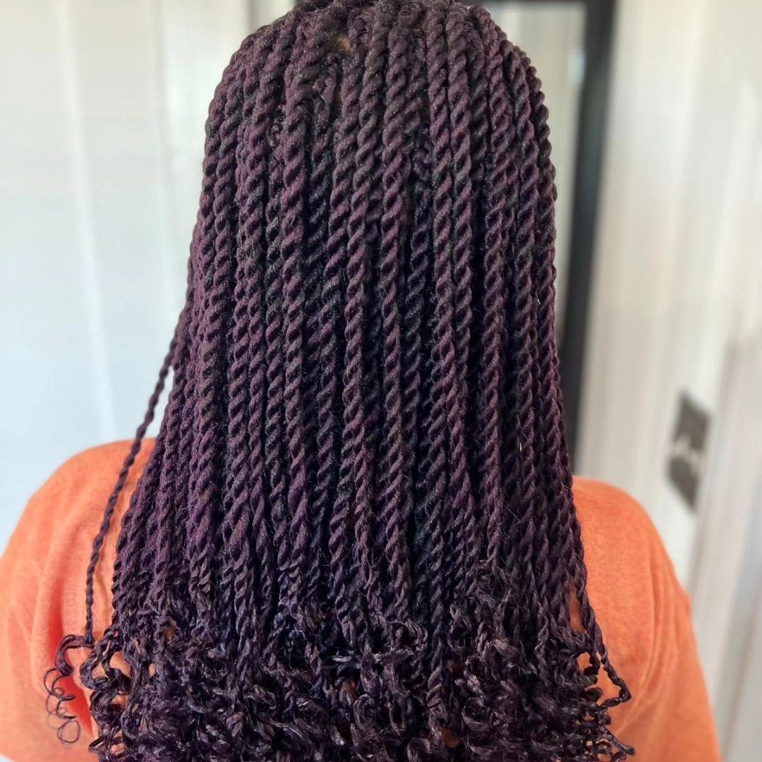 Woman with long, burgundy-colored twists, wearing an orange shirt.