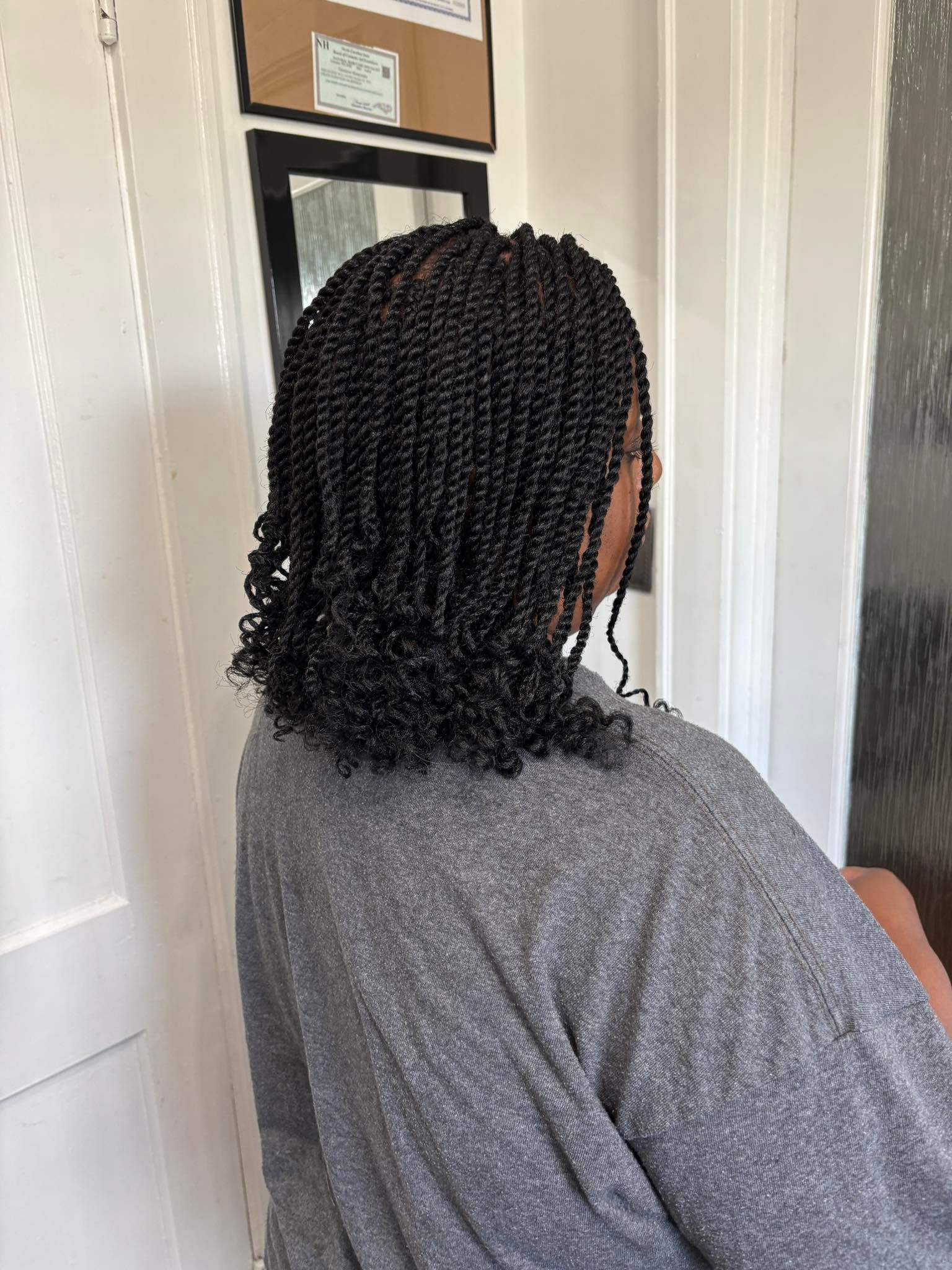 Person with black spring twist braids, wearing a gray sweater.