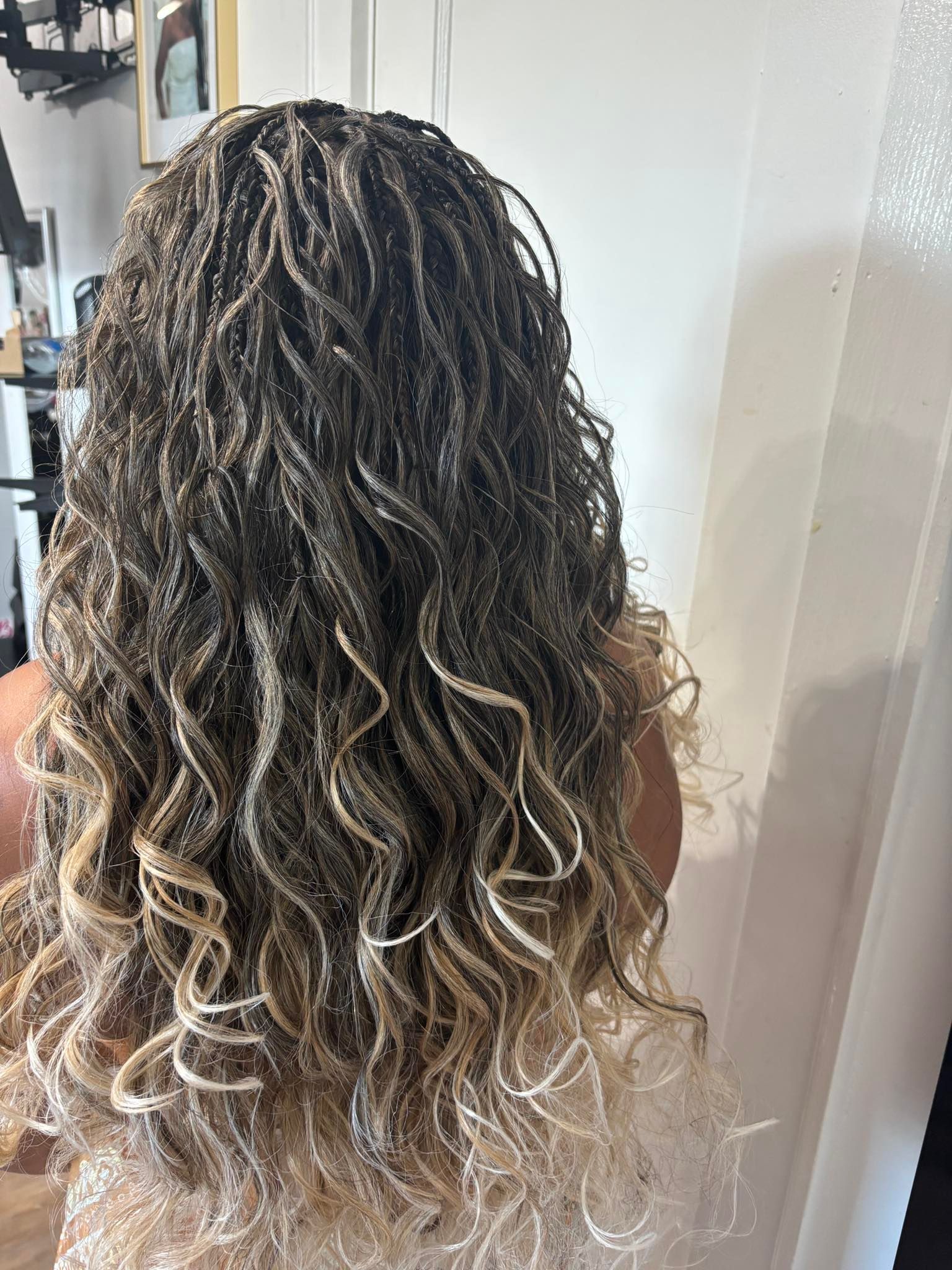 Woman with long, curly micro braids, ombre effect from dark to light blonde.