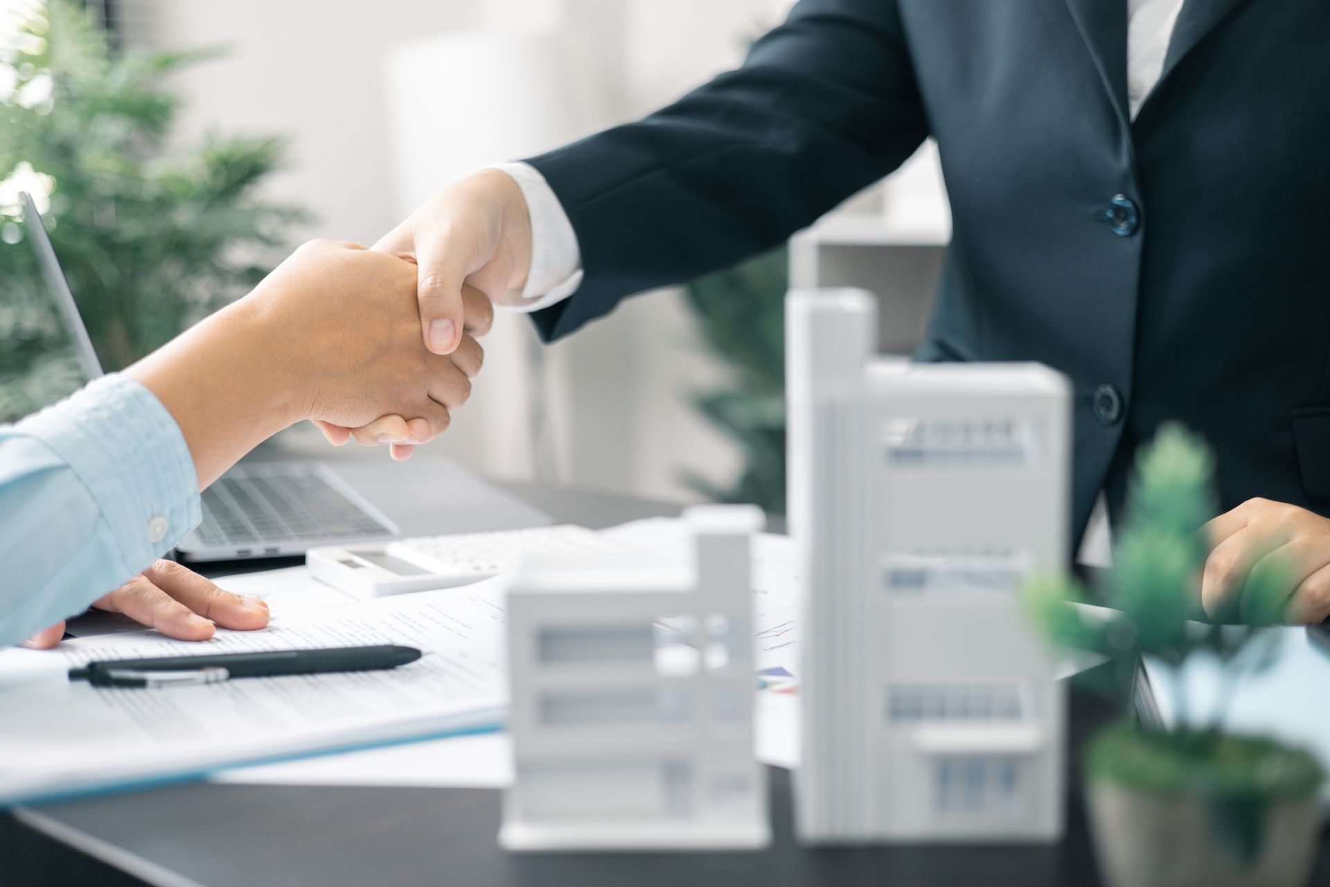 A man and a woman are shaking hands over a table.