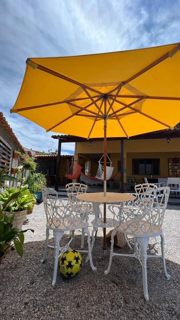 Um guarda-chuva amarelo está sobre uma mesa e cadeiras.