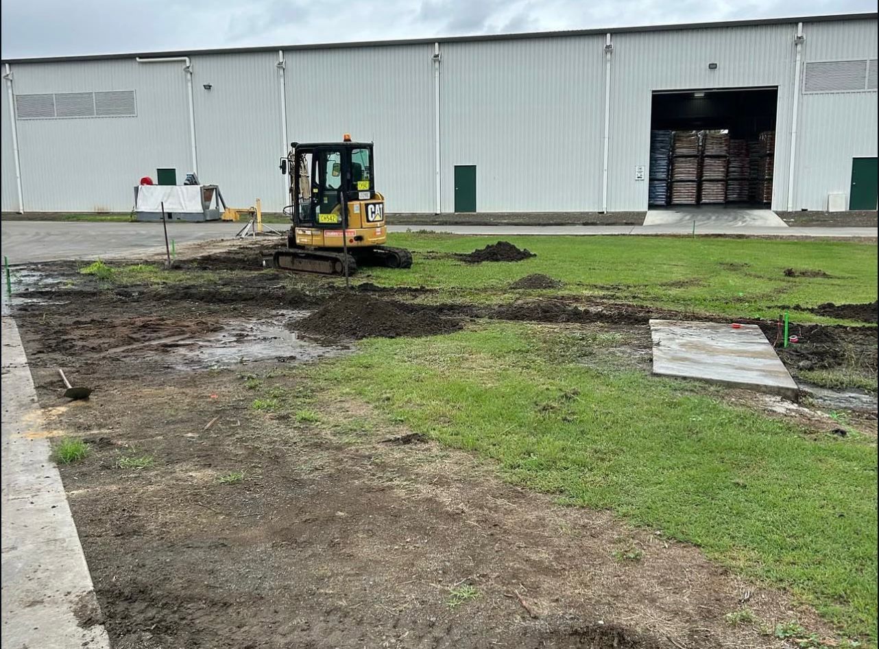 Small Excavator on Muddy Ground in Front of a Warehouse — Chief Structural Landscaping In Gold Coast, QLD