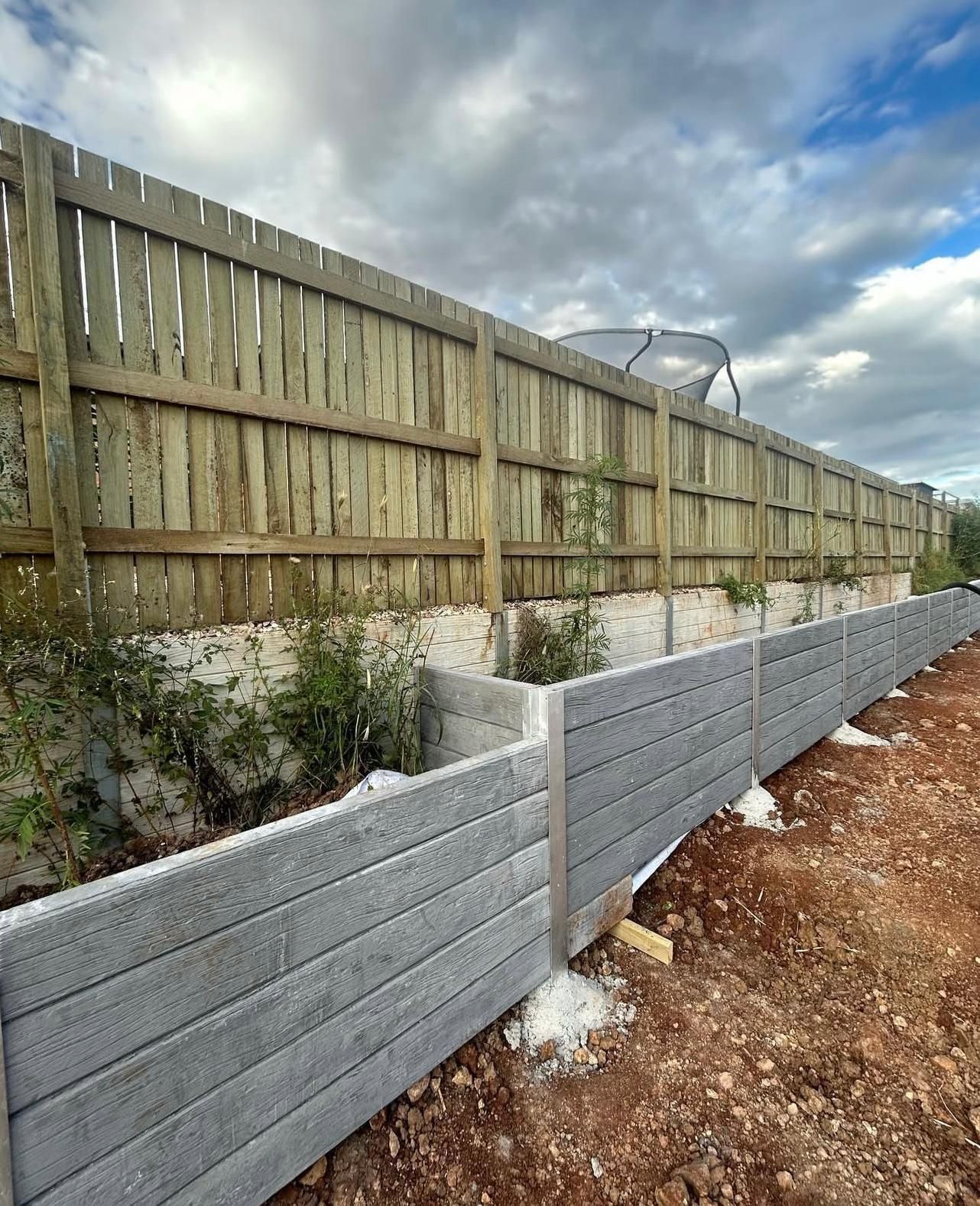 Wooden Fence Atop a Retaining Wall, Under a Cloudy Sky — Chief Structural Landscaping In Glenvale, QLD