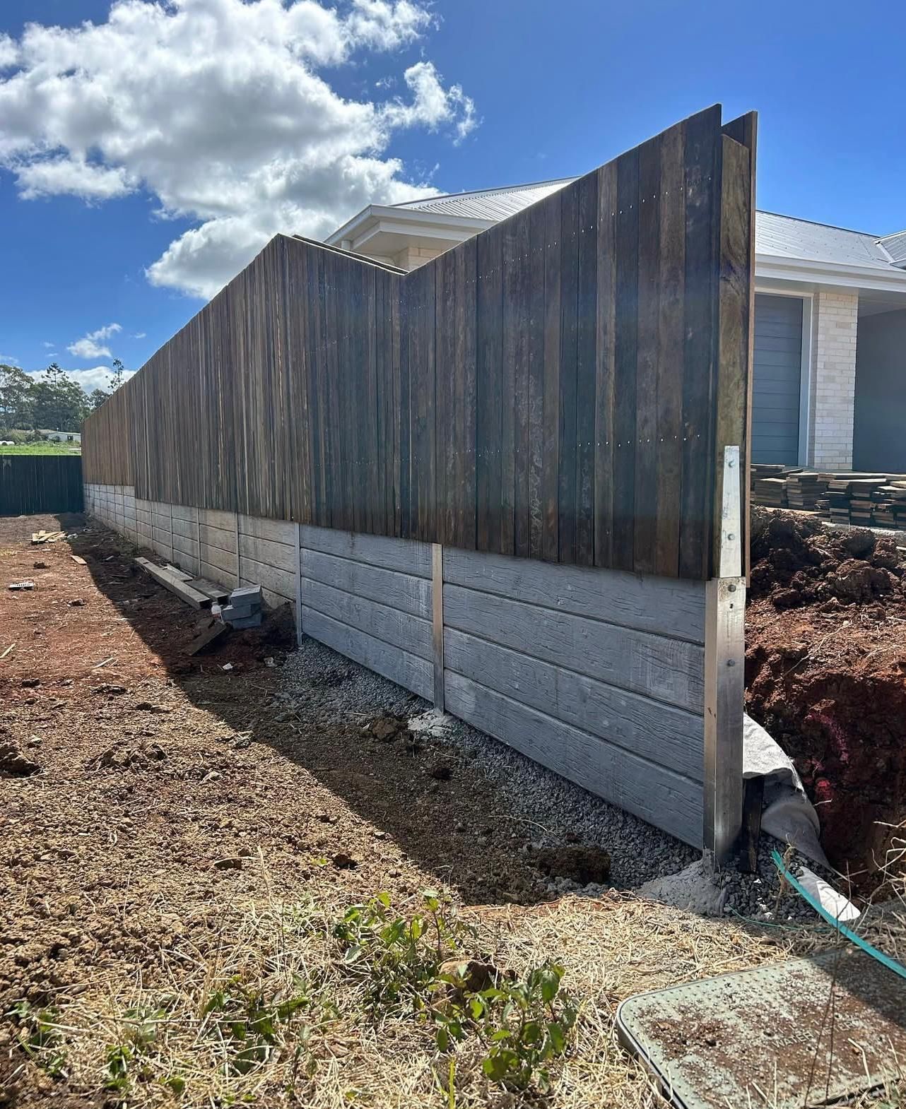 Wooden Fence Atop Gray Concrete Blocks Along a Yard, Under a Blue Sky — Chief Structural Landscaping In Darling Downs, QLD