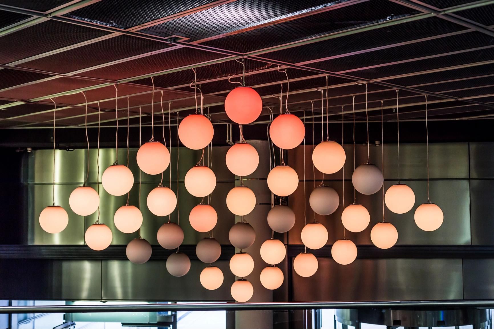 Ceiling fixture: multiple glowing orbs in a diamond pattern, various shades of peach and grey.