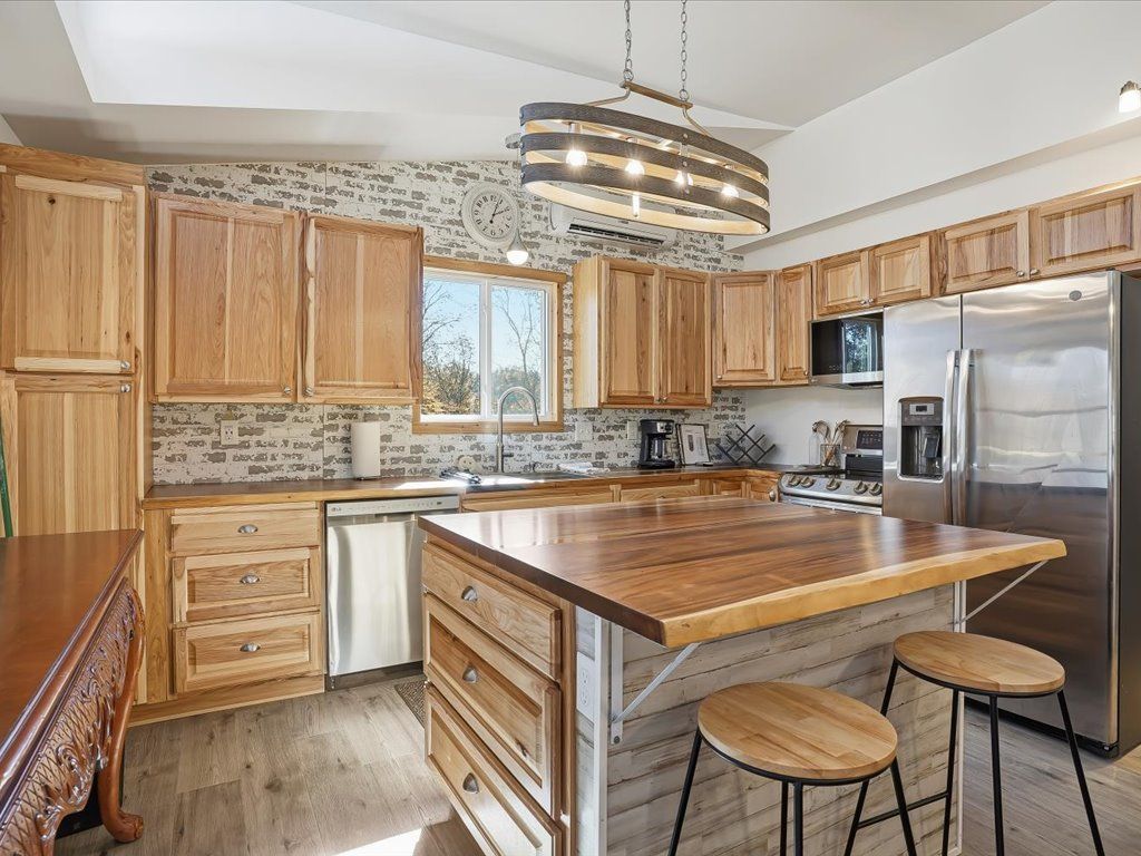 Modern kitchen with wood cabinets, stainless fridge, island, bar stools, and patterned backsplash
