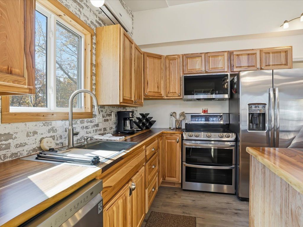 Full Kitchen with Double oven Bright kitchen with wood cabinets, stainless steel appliances, window over sink, and tiled backsplash.