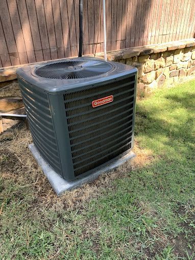 A large air conditioner is sitting on top of a concrete platform in the grass.