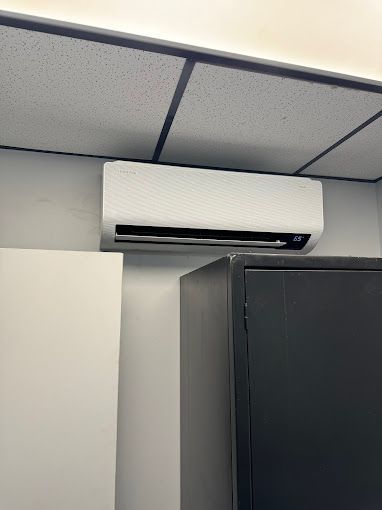 A white air conditioner is hanging from the ceiling in a room.