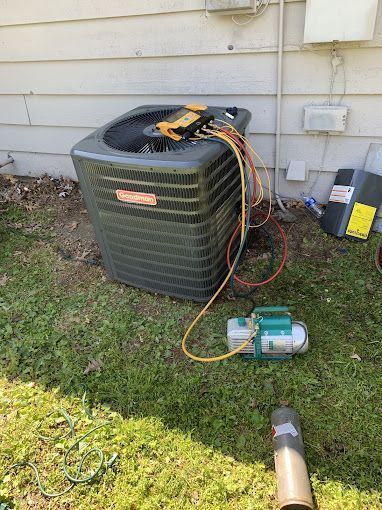 An air conditioner is being serviced in the backyard of a house.