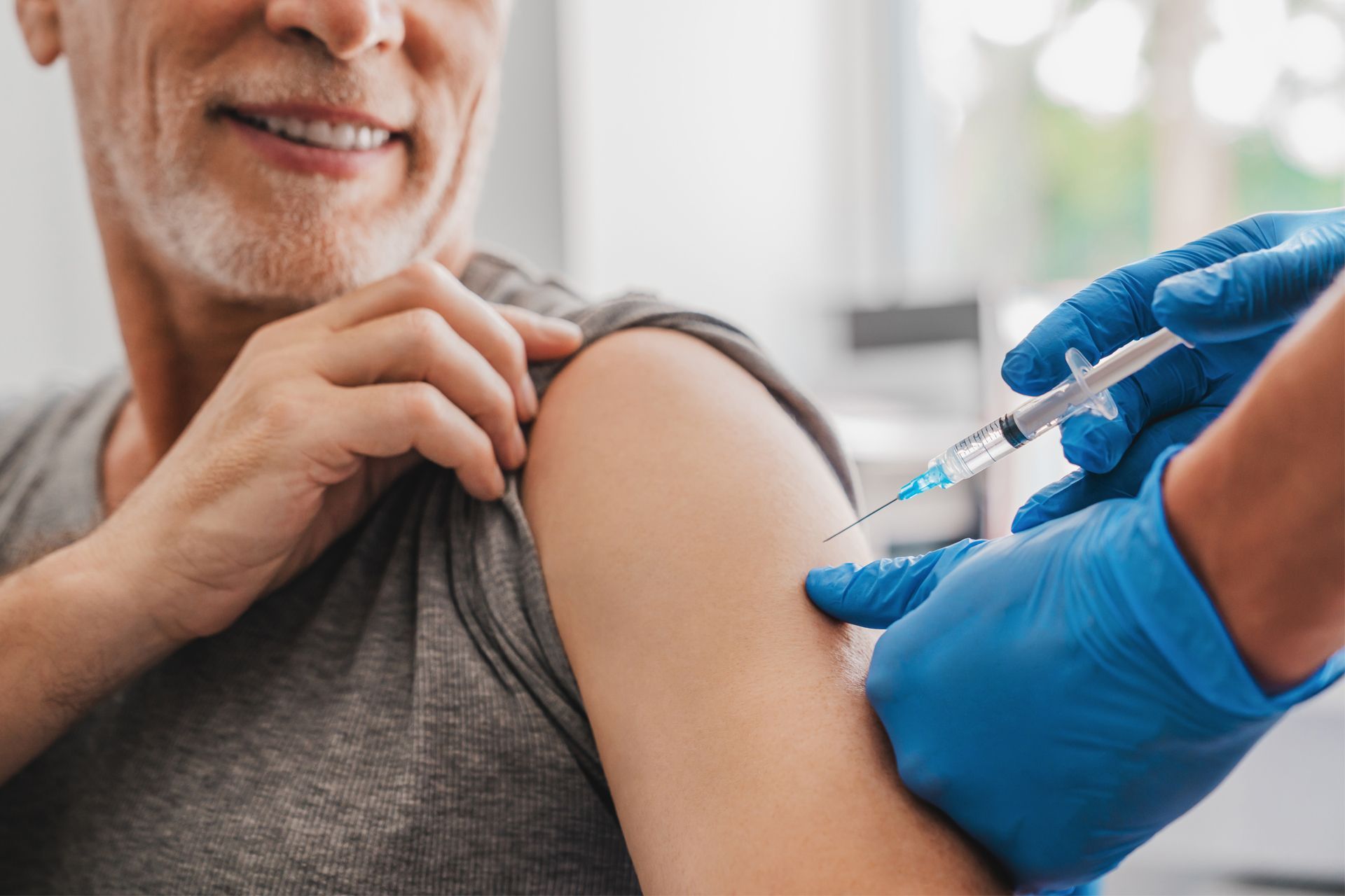 A man wearing a mask is getting a vaccine from a doctor