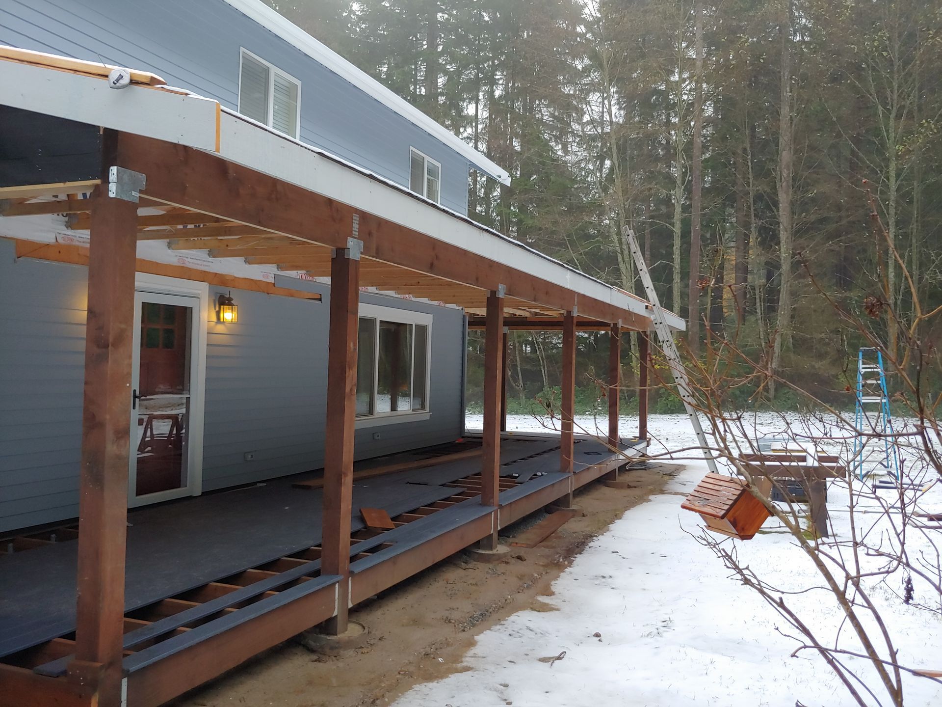 A blue house with a wooden porch in the snow