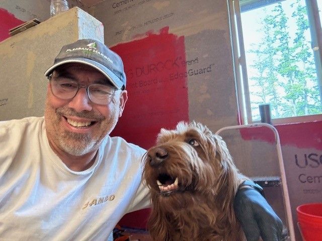 A man and a brown dog are posing for a picture