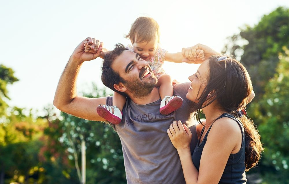 A man and woman are holding a baby on their shoulders.