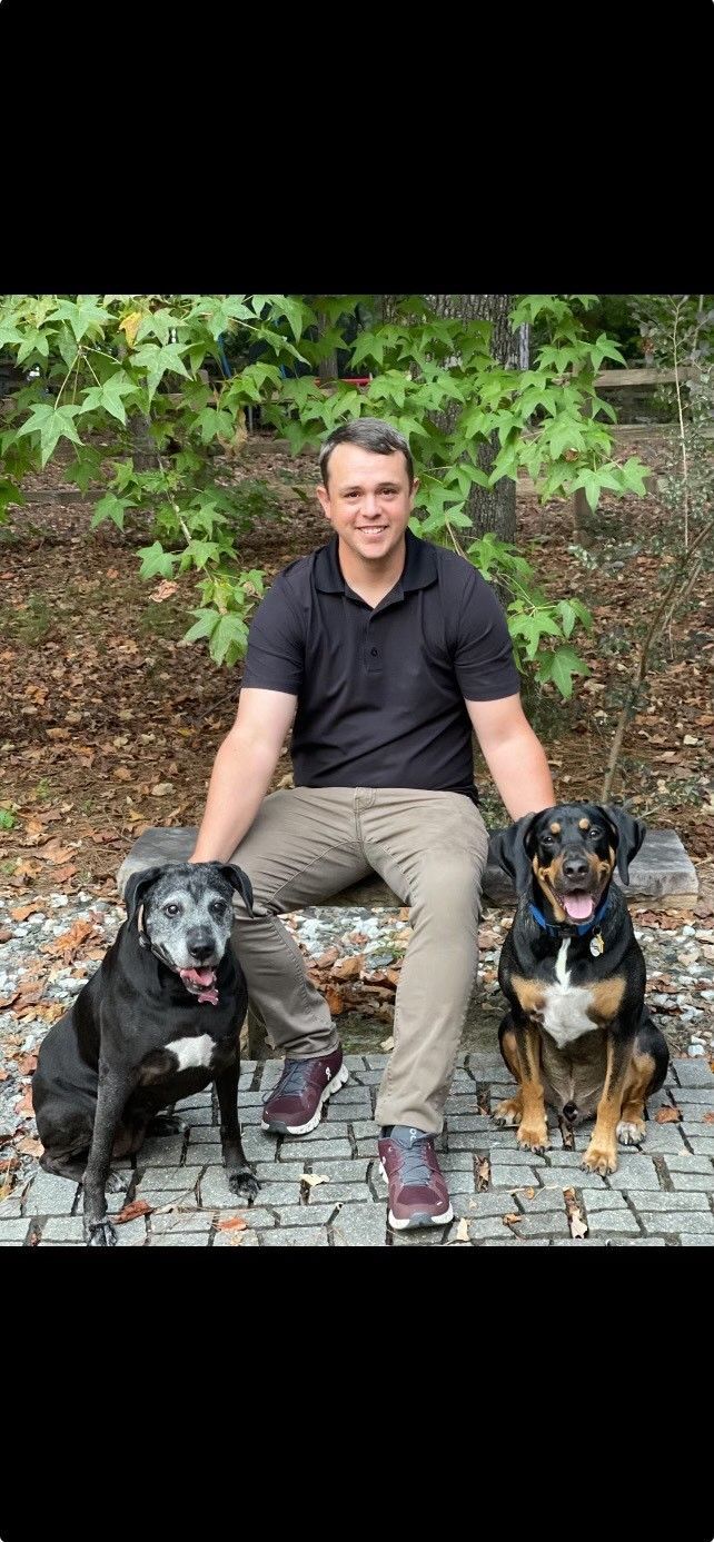 A man is sitting on a bench with two dogs.