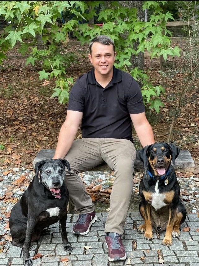 A man is sitting on a bench with two dogs