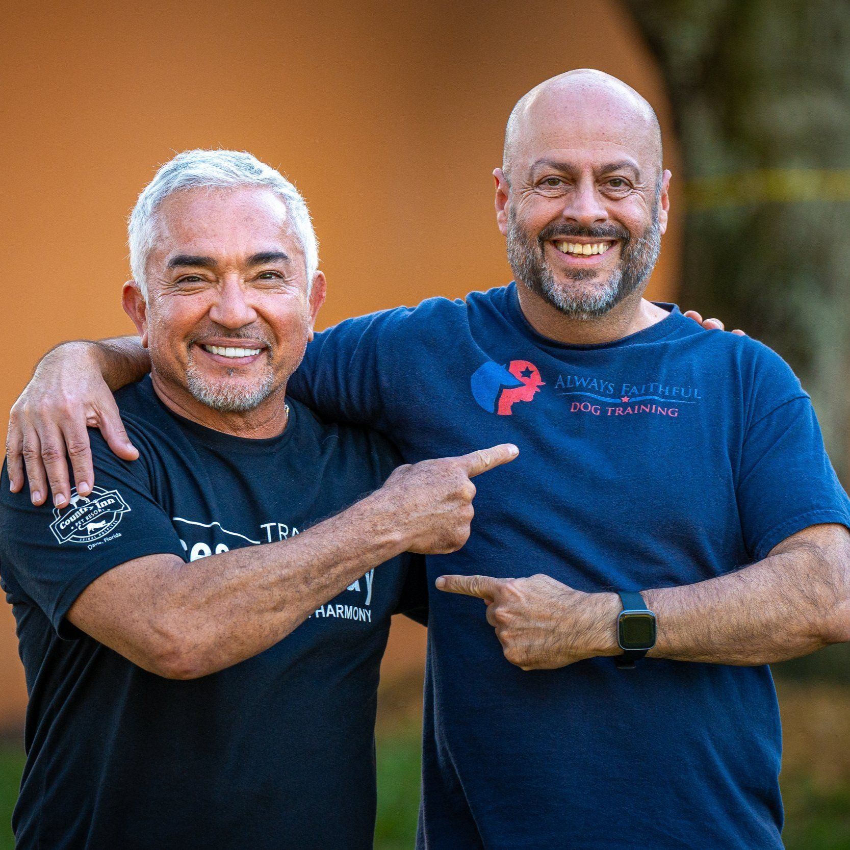 Two men are posing for a picture and one of them is pointing at the camera.
