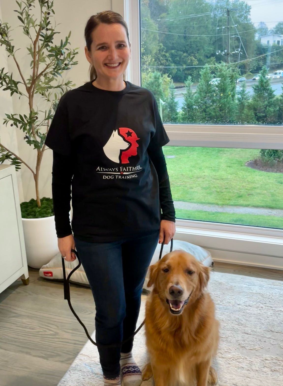 A woman in a black shirt is standing next to a dog on a leash