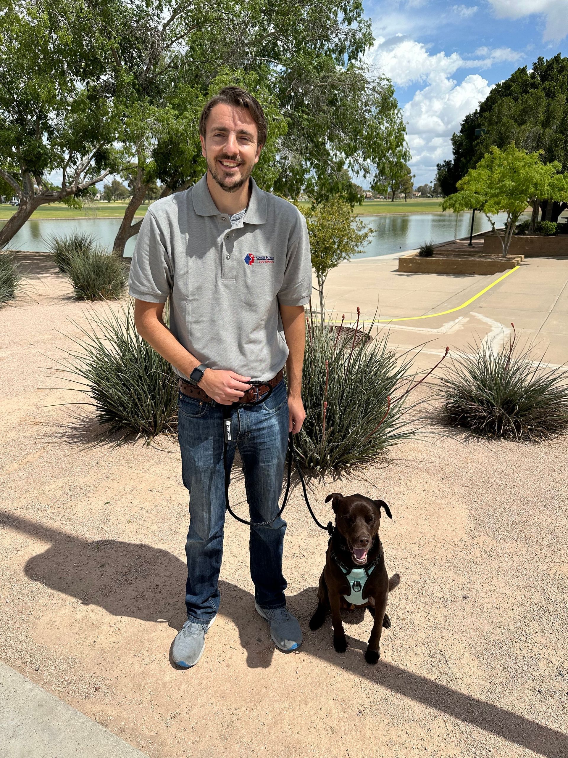 A man is standing next to a brown dog on a leash.