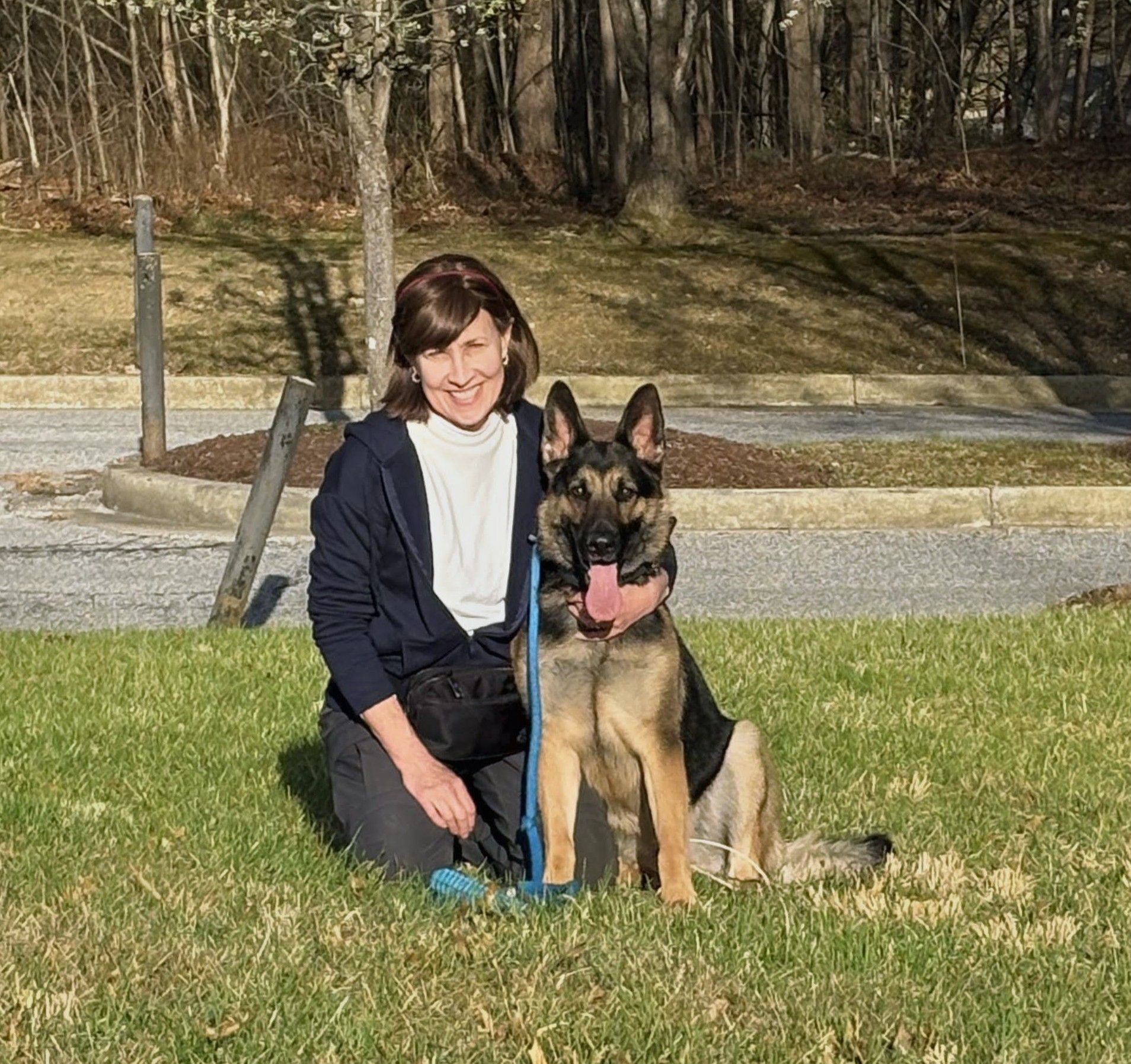 A woman is kneeling down next to a dog on a deck.