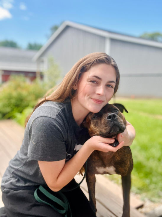 A woman is holding a brown dog in her arms.