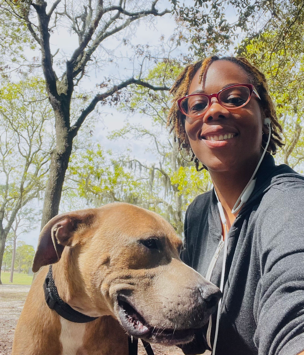 A woman is taking a selfie with her dog in a park.