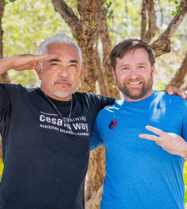 Two men are posing for a picture and one has a cesar 's way shirt on