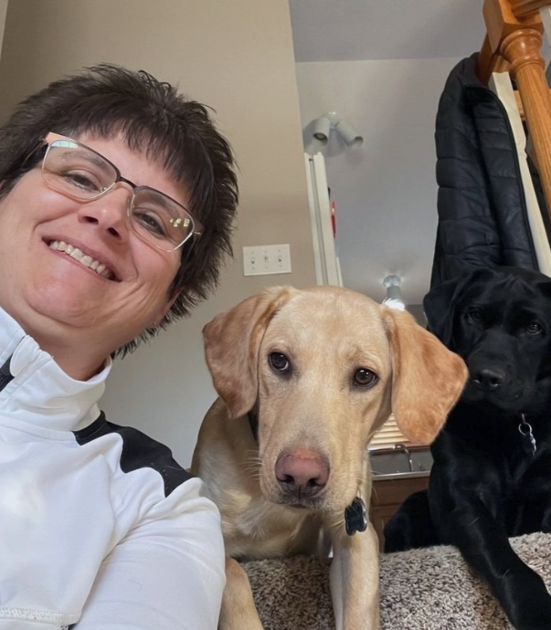 A woman wearing glasses takes a selfie with her dog