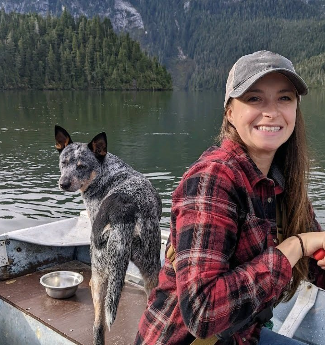 A woman is sitting in a boat with a dog.