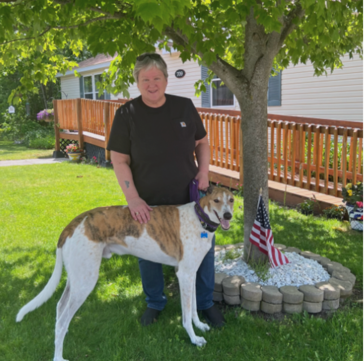 A man standing next to a brown and white dog