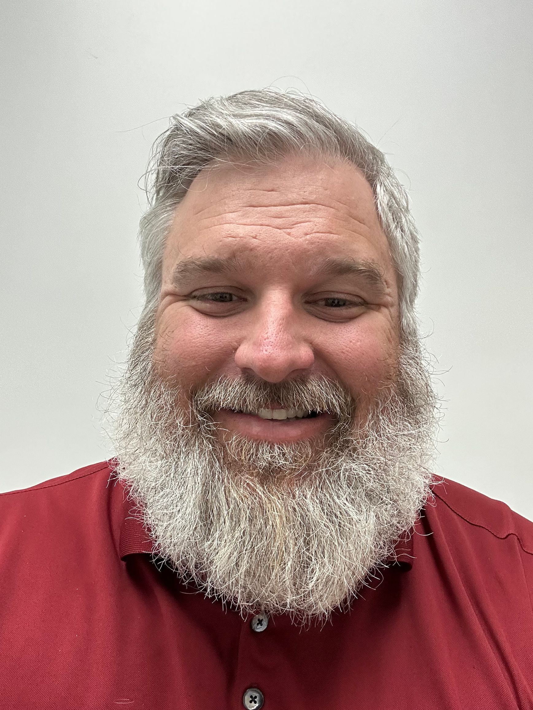 A bald man wearing glasses and a black shirt is standing in the desert.