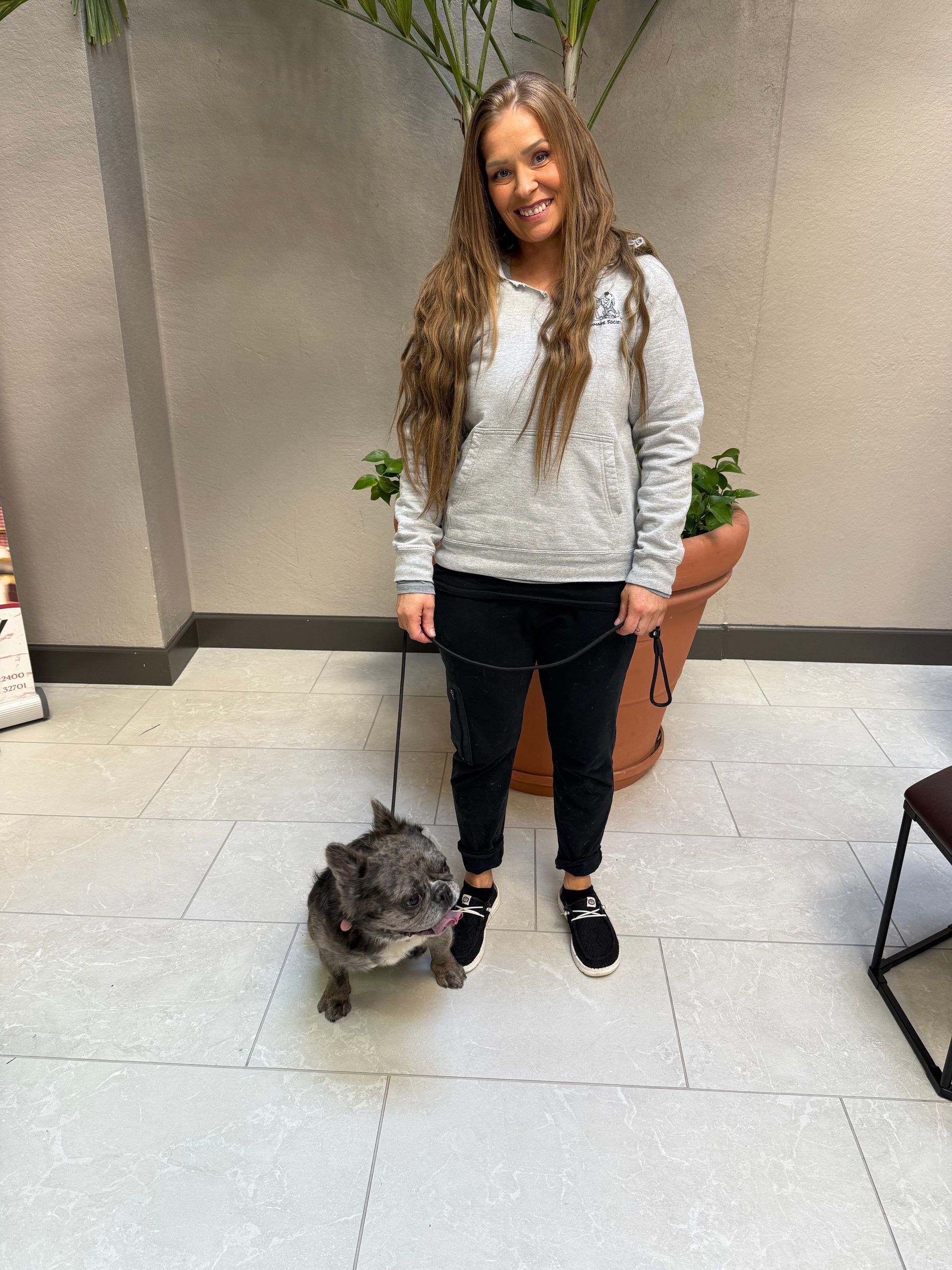 A woman is sitting on a couch with a large black dog.