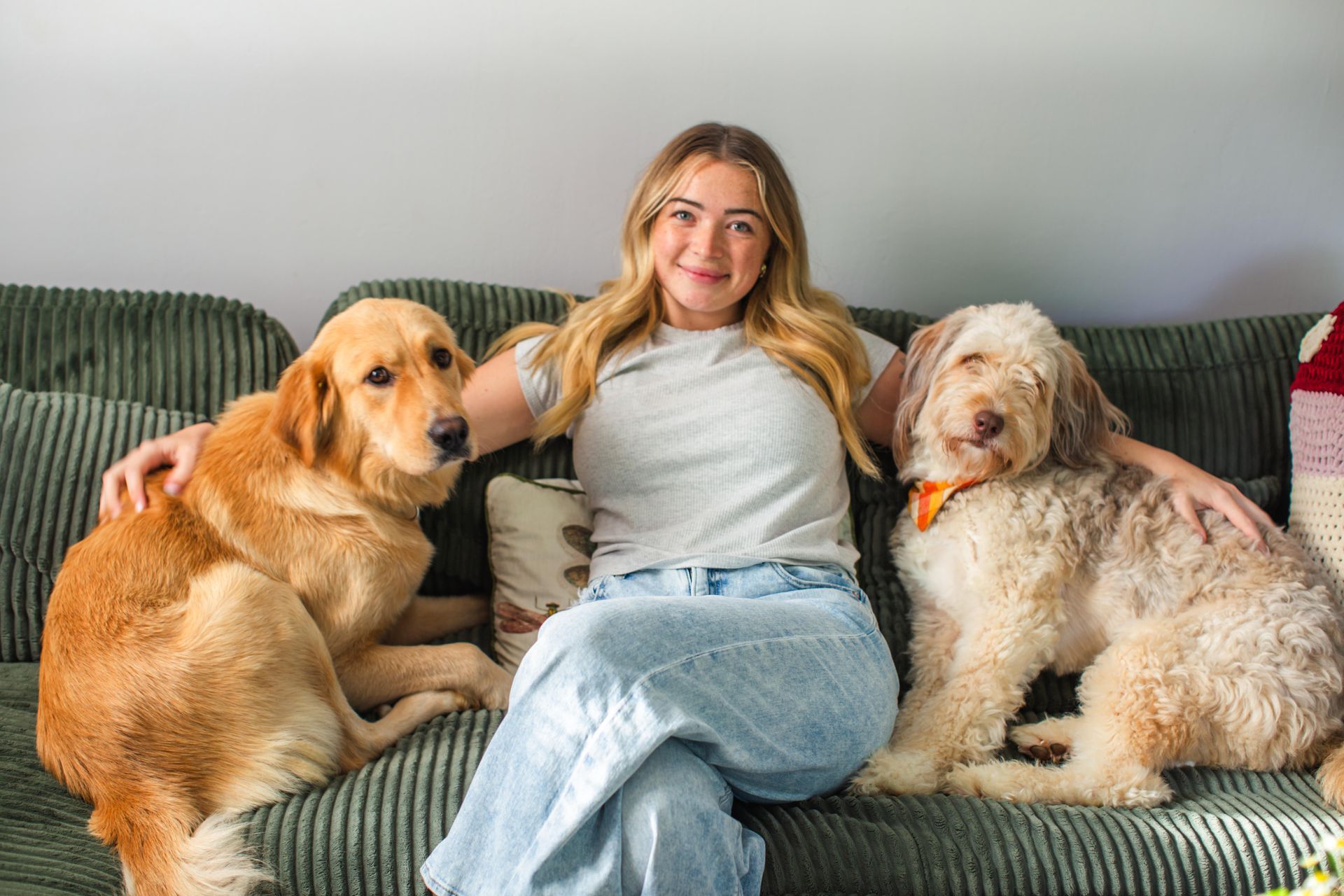 A woman in a purple shirt is sitting next to a dog on a wooden deck.