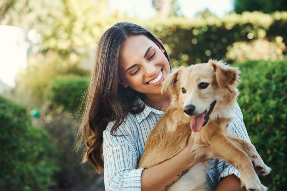 A woman is holding a dog in her arms and smiling.