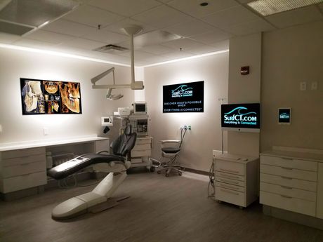 A dental office with a dental chair and a monitor