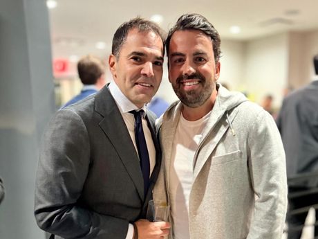 Two men in suits and ties are posing for a picture.