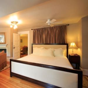 Bedroom with a large bed, brown curtains, and a bedside lamp.