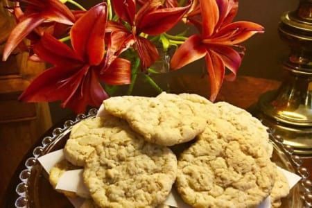 Cookies on a glass plate, with red flowers in the background.
