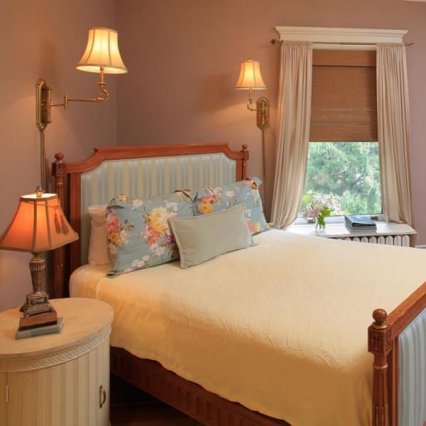 Bedroom with bed, nightstand, lamps, window, and mauve walls.