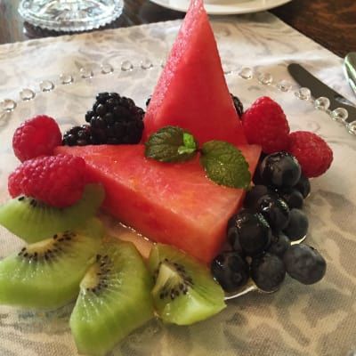 Fruit salad with watermelon, kiwi, raspberries, blackberries, blueberries, and mint on a decorative plate.