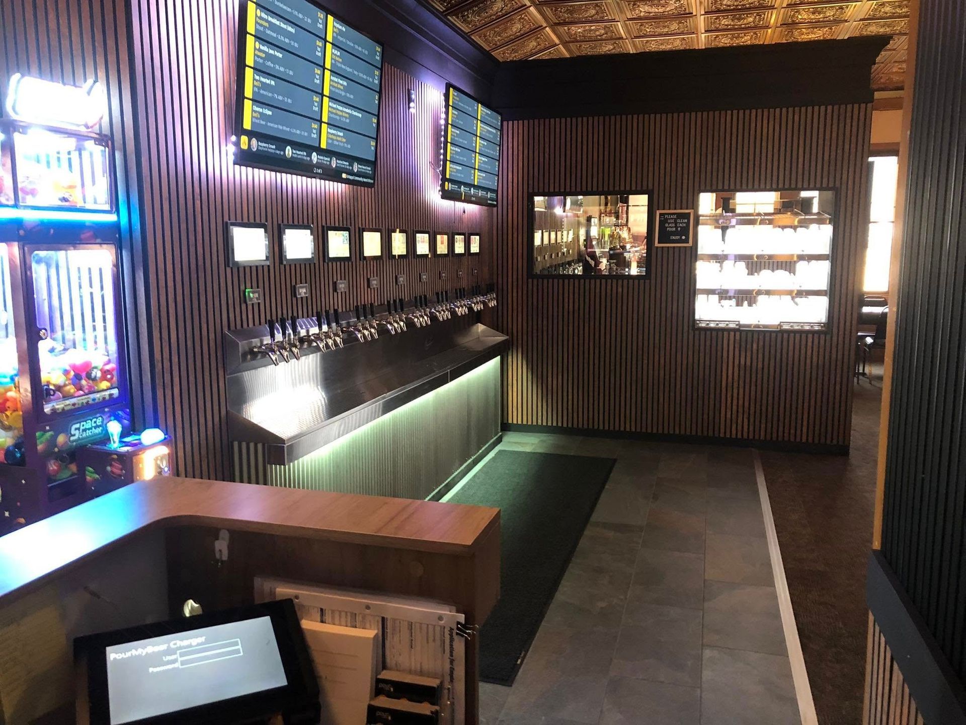 Bar with multiple beer taps, screens showing menu, and wood paneling.