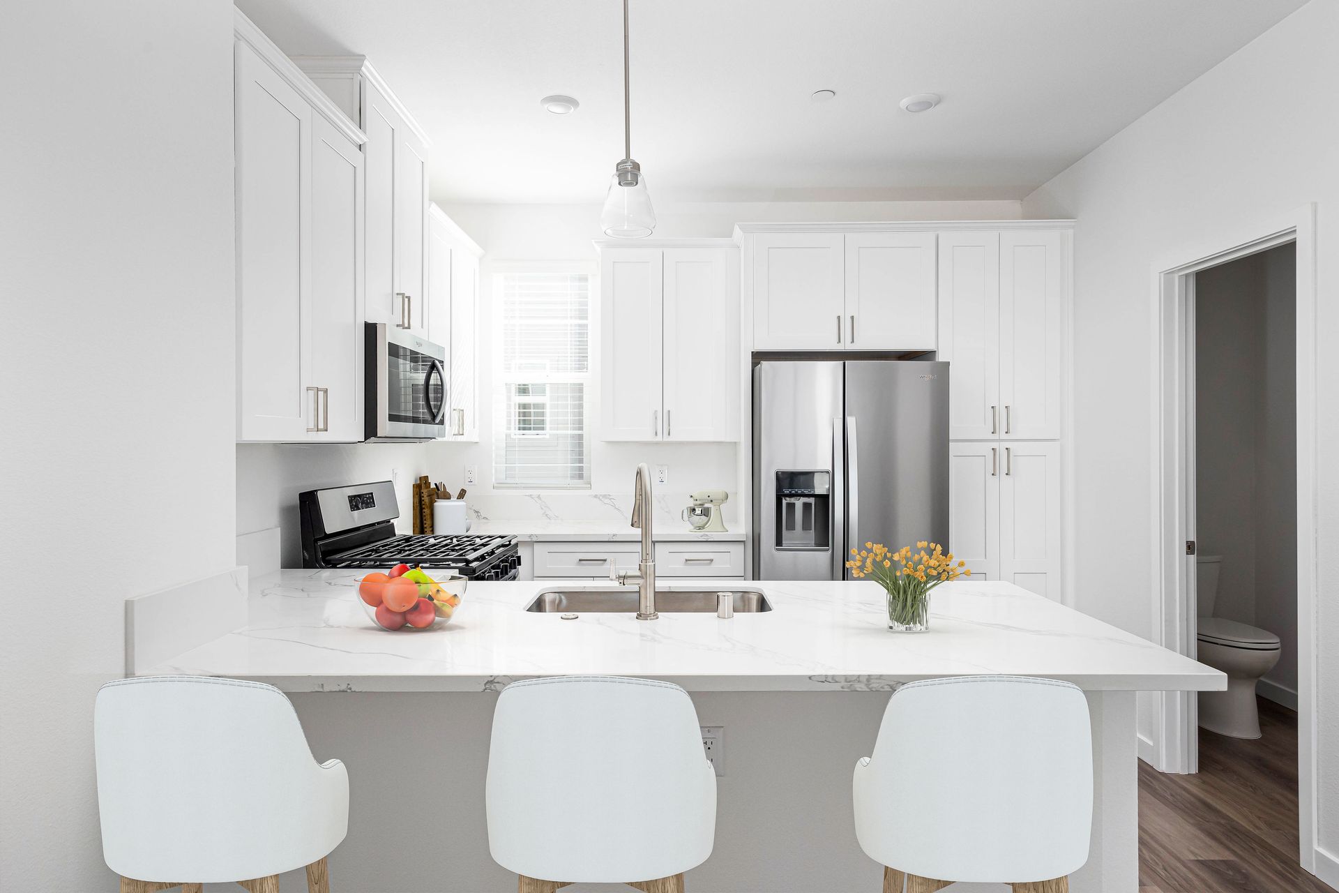 a kitchen with white cabinets , stainless steel appliances , a sink , and a refrigerator .