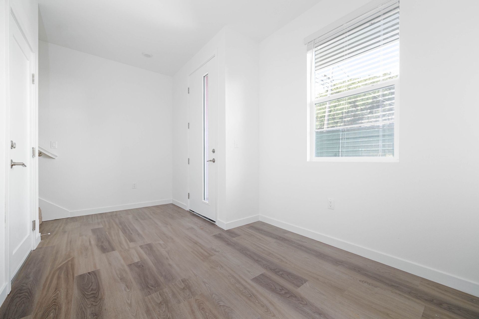 an empty room with hardwood floors and a window .