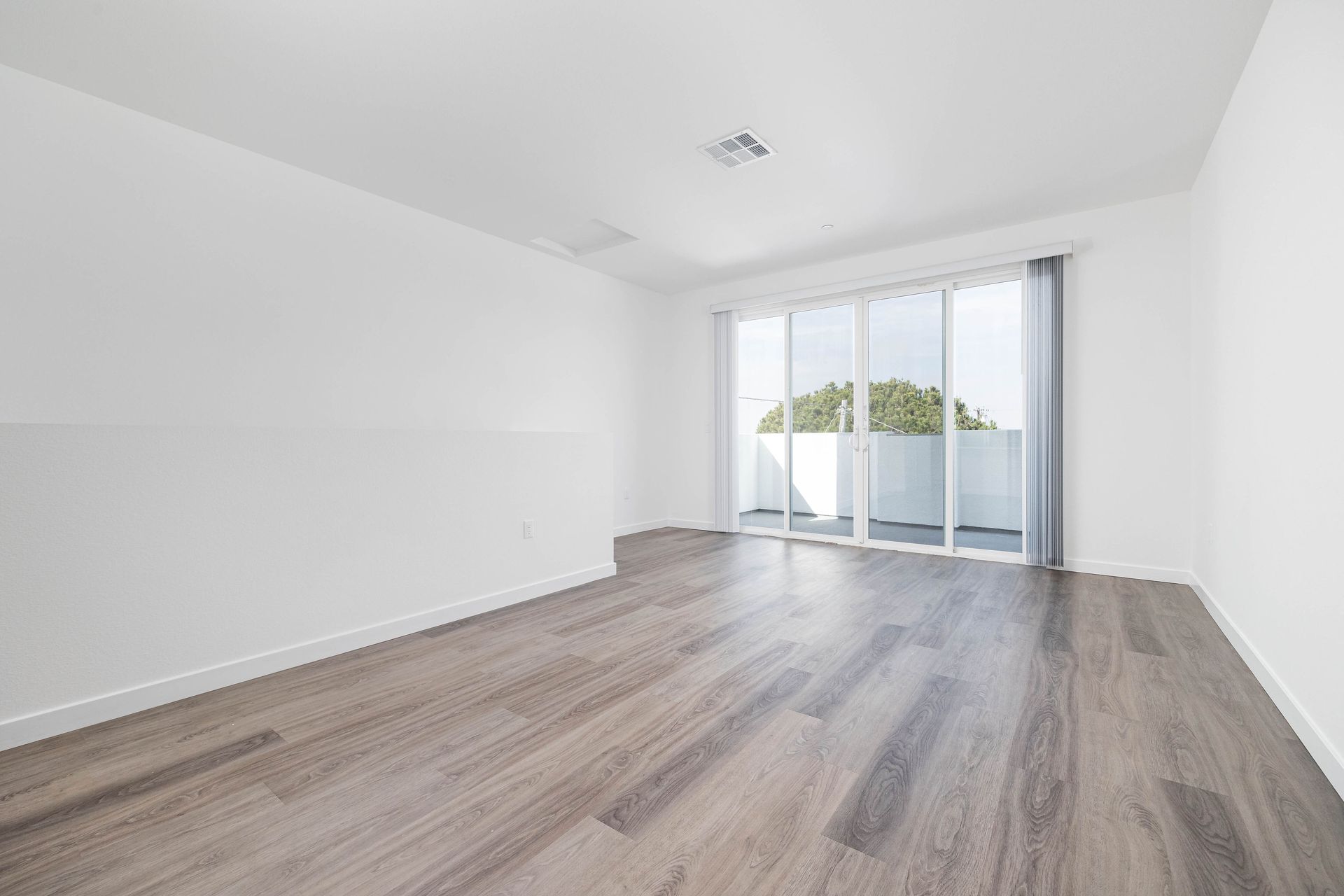 an empty living room with hardwood floors and sliding glass doors .