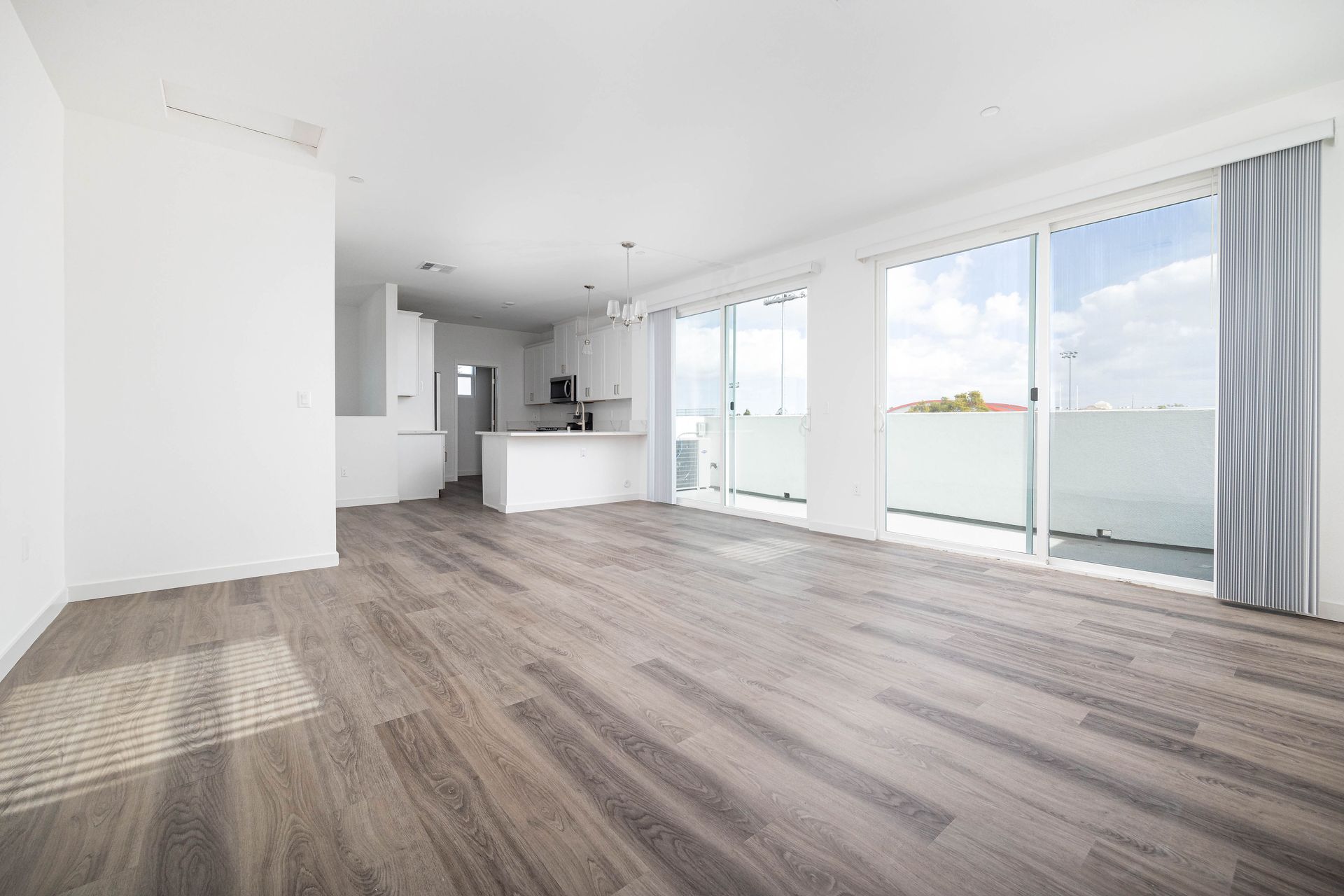 an empty living room with hardwood floors and sliding glass doors .