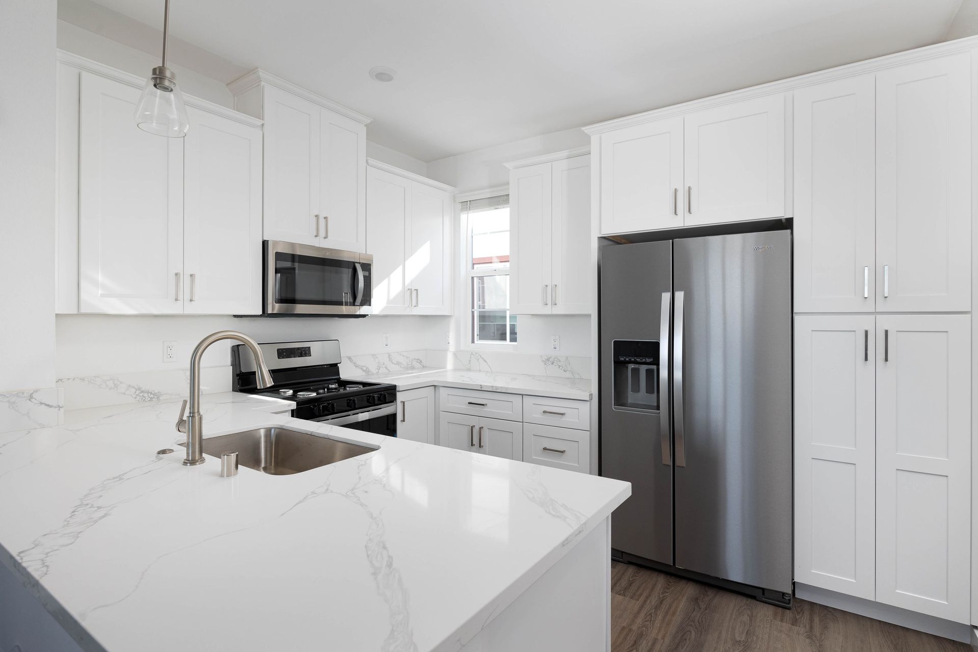 a kitchen with white cabinets , stainless steel appliances , a sink and a refrigerator .