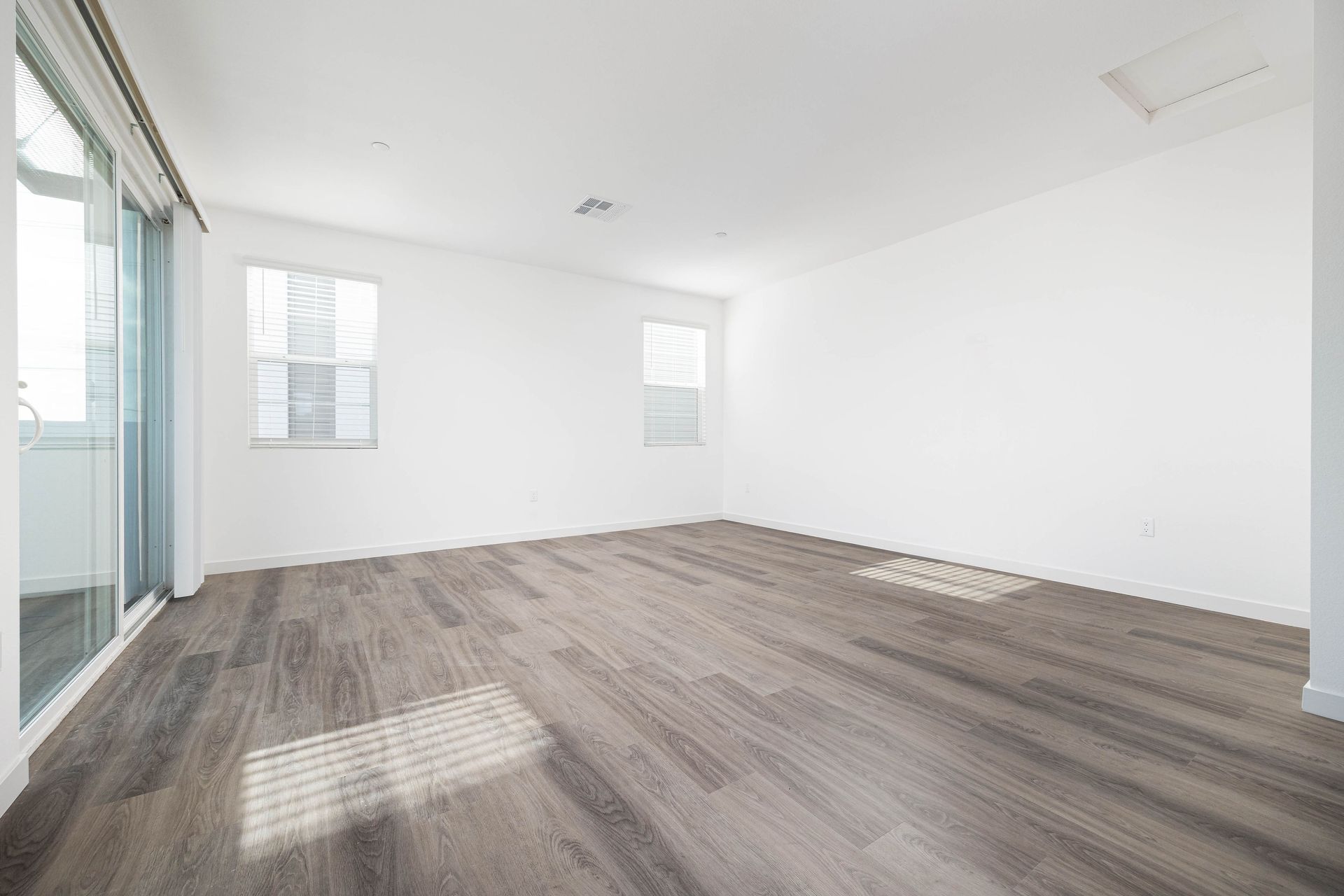 an empty living room with hardwood floors and white walls .