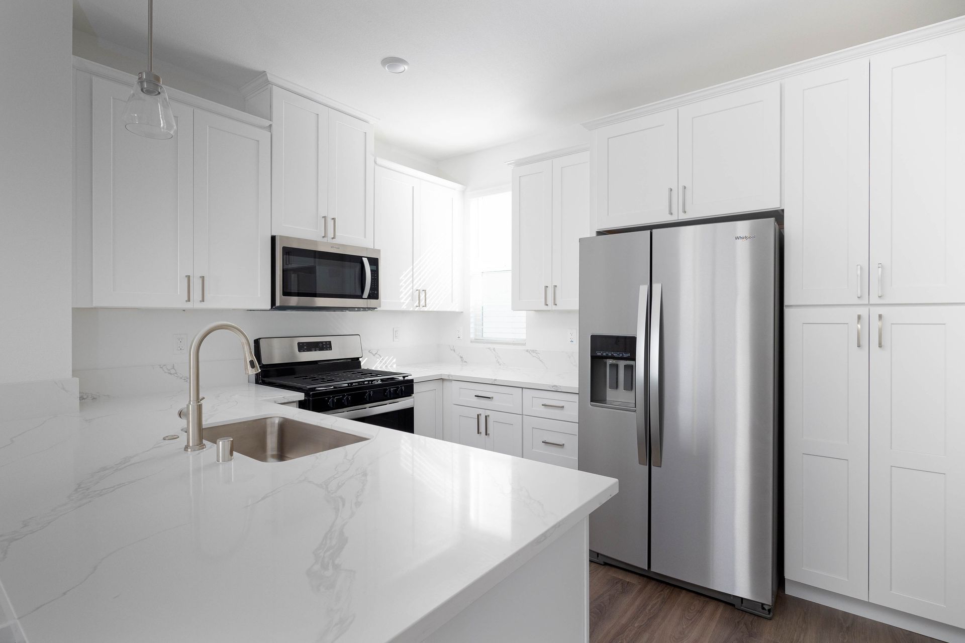 a kitchen with white cabinets , stainless steel appliances , a sink , and a refrigerator .